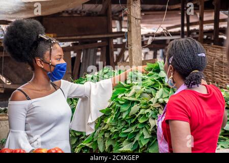 young african woman wearing a face mask shopping for food stuff in a local market Stock Photo