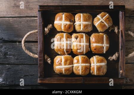 Hot cross buns in wooden tray served over old texture wood background. Top view, space. Easter baking. Stock Photo