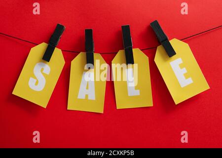 Sale text hanging on a clothesline with clothespins on a red background, a sale concept for discount and Black Friday offers Stock Photo