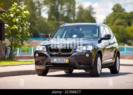 GRODNO, BELARUS - JUNE 2020: BMW X3 II F25 2.0i xDrive front three fourth view outdoors on sunny road background of summer city promenade flowering Stock Photo