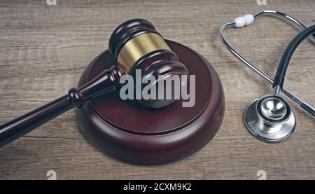 Judge's gavel beside medical stethoscope on wooden table. Medical law concept. Stock Photo