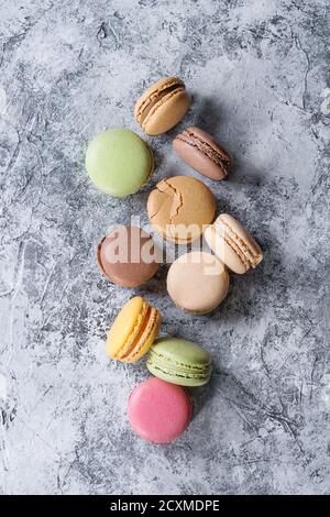 Variety of colorful french sweet dessert macaron macaroons with different fillings served over gray texture background. Top view with space Stock Photo