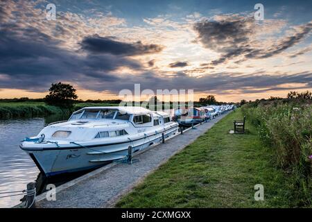 Boats moored on the River Bure for the night near St. Benet's Abbey, Norfolk Broads. Stock Photo