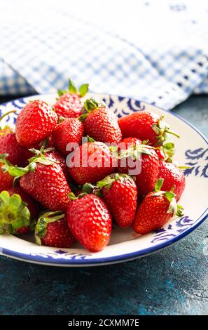 Heap of fresh strawberries in ceramic bowl on stone background. Stock Photo