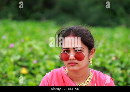 close-up portrait of An Indian young attractive stylish blonde woman posing in outdoors nature in summer fashion style traditional dress wearing sungl Stock Photo