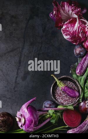 Assortment raw organic of purple vegetables mini eggplants, spring onion, beetroot, radicchio salad, plums, kohlrabi, flower salt over dark metal back Stock Photo