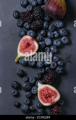Variety of fresh berries blueberry, dewberry and figs over dark metal background. Top view with space. Stock Photo