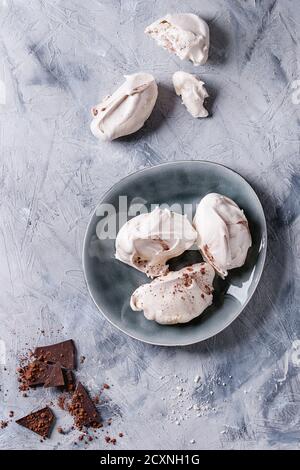 Baking homemade french dessert meringue with chocolate served with dark chopping chocolate and cocoa powder on gray ceramic plate over gray concrete t Stock Photo