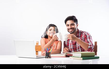 Cute Indian girl with father studying or doing homework at home using laptop and books - online schooling concept Stock Photo