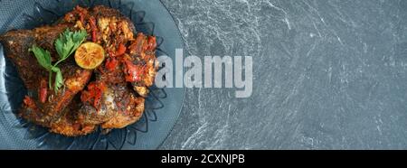 Homemade fried parrot fish with chilli is asian culinary food, served on a stone pad Stock Photo