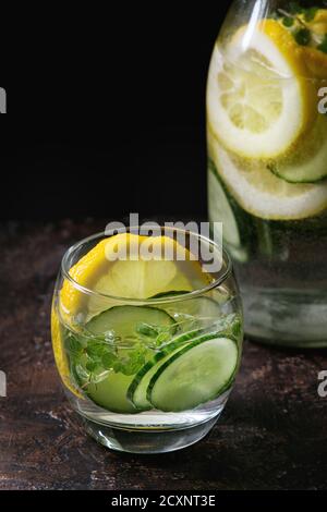 Citrus cucumber sassy sassi water for detox in glass bottle on dark black background. Clean eating, healthy lifestyle concept, sunlight Stock Photo