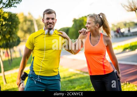 Young couple is exercising outdoor. They are and stretching and warming up for jogging. Stock Photo