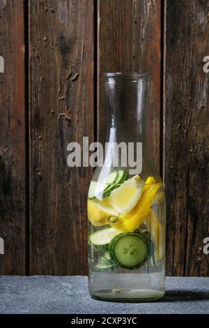 Citrus cucumber sassy sassi water for detox in glass bottle on wooden background. Clean eating, healthy lifestyle concept, sunlight Stock Photo