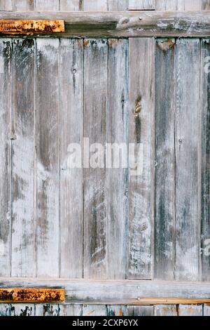 The texture of wooden planks is gray-blue. Close-up of a gray fence with rusty fittings. Stock Photo