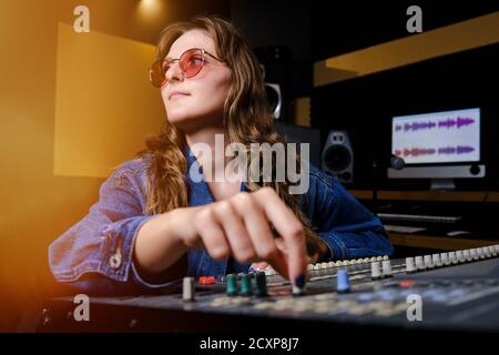 Woman sound engineer at the mixing Board. The girl at the remote in the recording Studio. Professional recording of musicians in the Studio. Stock Photo