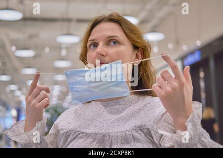 Adult woman puts on face mask on city street Stock Photo