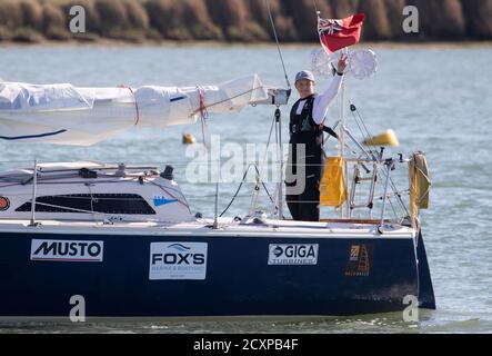 15-year-old Timothy Long waves towards the shore as he sails his 28ft boat 'Alchemy' into Hamble Point Marina, Hampshire, becoming the youngest person to sail solo around Britain. Stock Photo