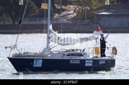 15-year-old Timothy Long waves towards the shore as he sails his 28ft boat 'Alchemy' into Hamble Point Marina, Hampshire, becoming the youngest person to sail solo around Britain. Stock Photo