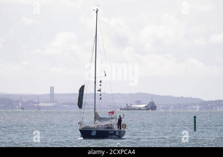 15-year-old Timothy Long waves towards the shore as he sails his 28ft boat 'Alchemy' into Hamble Point Marina, Hampshire, becoming the youngest person to sail solo around Britain. Stock Photo