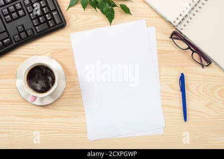 Flat lay, top view office table desk. Workspace with blank sheet of paper, keyboard, office supplies, pencil, green leaf, and coffee cup on wooden tab Stock Photo