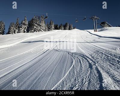 Three single traces at ski slope underneath a chairlift in the Austrian alps against blue sky Stock Photo
