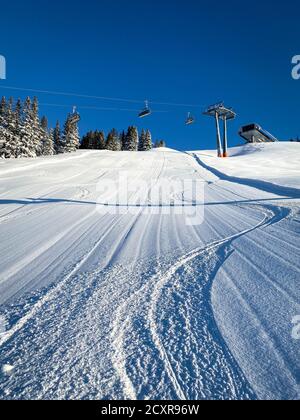Three single traces at ski slope underneath a chairlift in the Austrian alps against blue sky Stock Photo