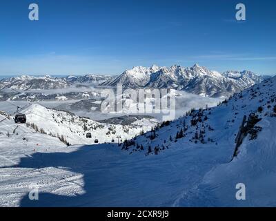 Scenic view of snow covered Lofer Mountains (right) and ski slopes of Fieberbrunn in the Austrain alps against blue sky Stock Photo