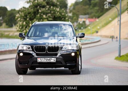 GRODNO, BELARUS - JUNE 2020: BMW X3 II F25 2.0i xDrive selective focus front view with wheels turned outdoors on sunny road summer city promenade with Stock Photo