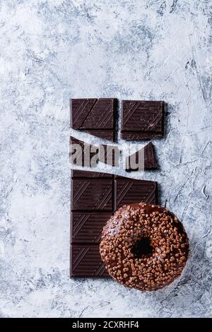Chocolate glazed donut on chopped chocolate over gray texture background. Top view with space Stock Photo