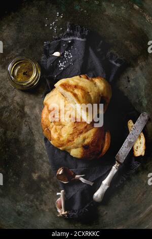 Homemade white wheat garlic bread on textile napkin with salt, olive oil and balsamic vinegar on old dark metal background. Top view with space Stock Photo