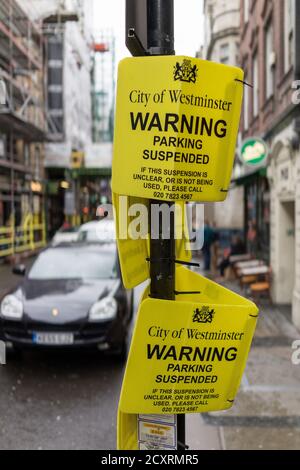 City of Westminster parking suspended signs attached to a sign post off of Broadwick Street. The Soho area of London’s West End on a cold and wet Janu Stock Photo