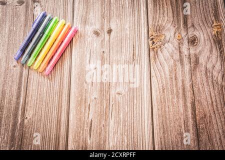 Colourful highlighter pens lined up to make a rainbow resting on a rustic wooden background with copy space Stock Photo