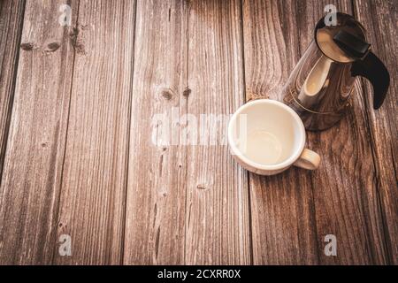 A silver coffee pot and white coffee cup on a rustic wooden background with copy space Stock Photo