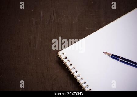 An empty blank white page of a notepad, placed over old wooden background. Stock Photo