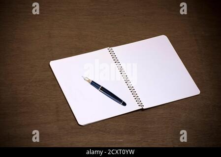 An empty blank white page of a notepad, placed over old wooden background. Stock Photo
