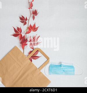 Red leaves of grapes, a paper bag and a medical mask. On white background. View from above . Autumn layout. High quality photo Stock Photo