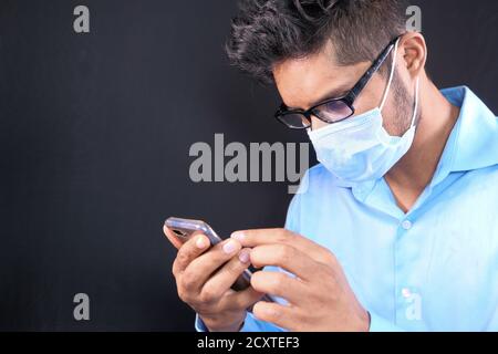 young man in face mask using smart phone on black background  Stock Photo