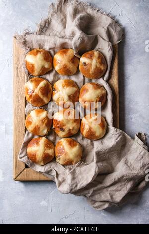 Homemade Easter traditional hot cross buns on wooden tray with textile over gray texture background. Top view, space Stock Photo