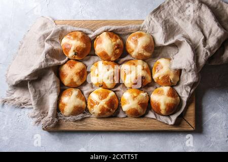 Homemade Easter traditional hot cross buns on wooden tray with textile over gray texture background. Top view, space Stock Photo