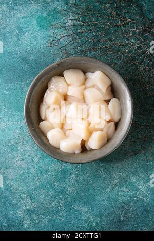 Raw uncooked scallops in vintage metal bowl over turquoise texture background. Top view, copy space Stock Photo