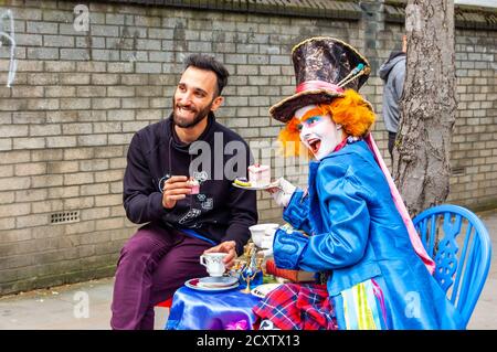 London, United Kingdom - September 16, 2017: Street artist playing Mad Hatter from Alice in wonderland drinking tee with cake and posing with the tour Stock Photo