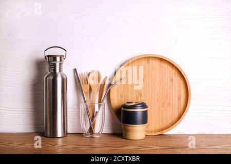 Eco set with bamboo cutlery, reusable water bottle and cup on wooden background. Stock Photo