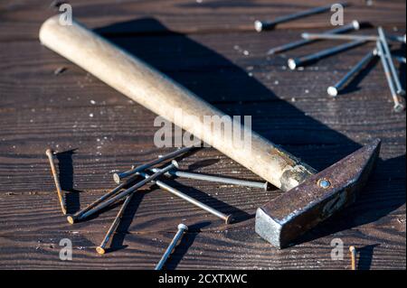 Old vintage hammer and nails on a wooden background, close-up, selective focus Stock Photo