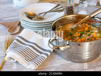vegetable soup with minced meat in a pot with ladle on wooden table Stock Photo