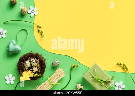 Easter background in green and yellow, copy-space.. Flat lay with quail eggs, freesia flowers and black heart confetti. Stock Photo