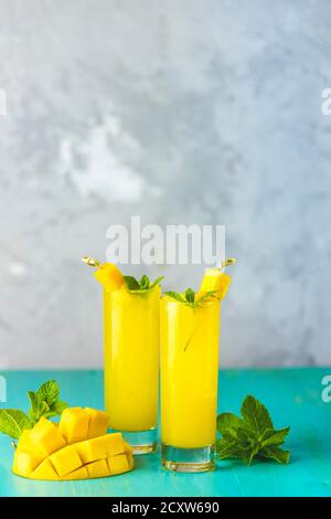 Refreshing summer cocktails made of mango, cold drink or a drink with ice on a blue gray background. Fresh summer ice cold mango cocktail or juice wit Stock Photo