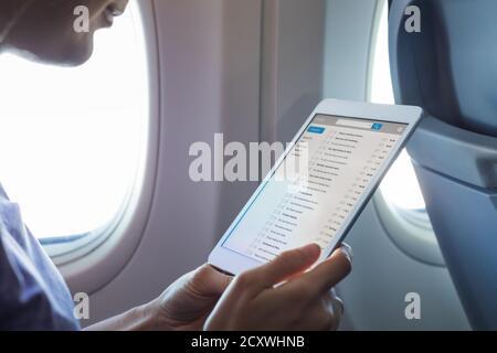 Working with email in airplane during flight with wifi internet network connection, passenger using tablet computer to communicate by e-mail in airpla Stock Photo