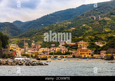 Great close-up view of the beach with the port, the medieval bell tower and the colourful buildings with the hills in the background in the old part... Stock Photo