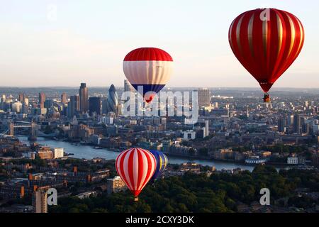Hot air balloons rise into the early morning sky in front of the city of London and Tower Bridge, July 25, 2011. Seven balloons took part in the flight over London as part of a collaboration between the London Sky Orchestra project, the 30th anniversary of the London International Festival of Theatre, and the Greater London Authority which is marking a year to go before the 2012 Olympic Games.   REUTERS/Andrew Winning (BRITAIN - Tags: TRANSPORT SOCIETY CITYSCAPE)