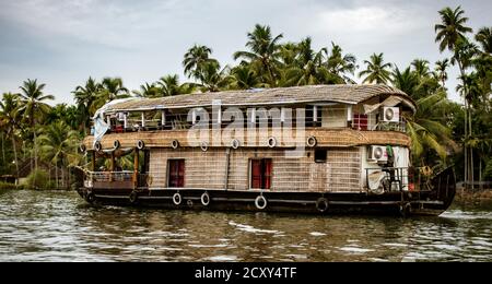 ALLEPPEY, INDIA, MAR 13, 2018: Bamboo thatched houseboat floats down the backwaters of Kerala Stock Photo